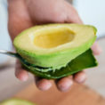 Person scooping out interior of avocado