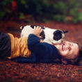 Child laughing while a puppy licks their face