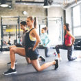 Group of people exercising doing lunges in gym
