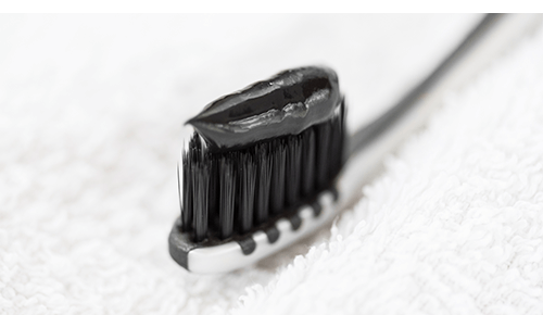 Black toothbrush with black charcoal toothpaste on top