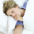 Woman coughing while lying in bed