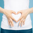 Person making a heart shape with hands over their stomach