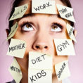 Stressed looking woman with lots of to-do post-it notes stuck to her face and head