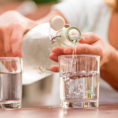 Person pouring water into glass from bottle