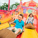 Children sliding down big slide at fair