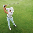 Person swinging golf club on green