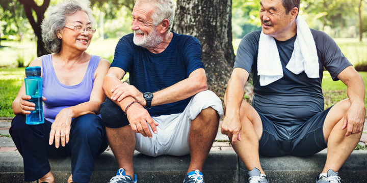 Three older adults sitting on curb after exercising