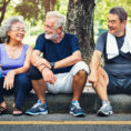 Three older adults sitting on curb after exercising