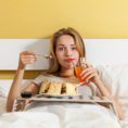 Sad person eating cake while lying in bed