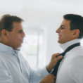 Older man tying his adult son's tie for a special event