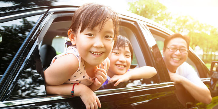 Father and children smiling while looking out car windows