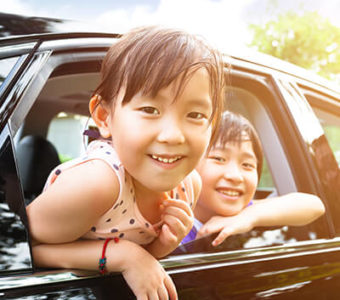 Father and children smiling while looking out car windows