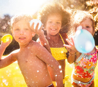 Group of children wearing swimsuits throwing water balloons