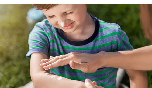 Parent applying sunscreen to child's arm