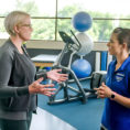 Woman talking to an Exercise Physiologist on a running track in a gym