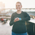 Smiling woman checking smart watch while walking along riverfront
