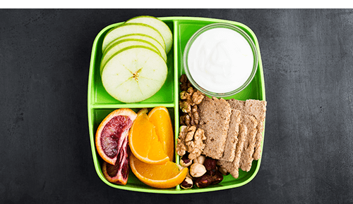 Lunch container with sliced fruit, nuts and crackers