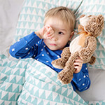 Child laying in bed with stuffed animal
