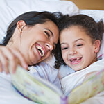 Mother and daughter reading a book in bed together