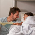 Dad reading a book to a child in bed at bedtime