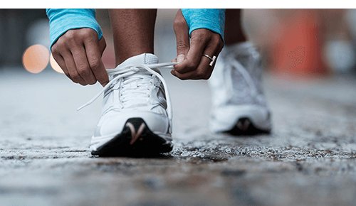 Closeup of a person tying their running shoe while on a walk