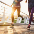 Closeup of two people running over bridge in the morning sunrise