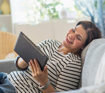 Woman laughing while looking at her digital tablet