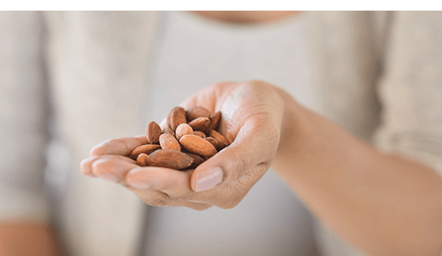 Person holding a handful of raw almonds