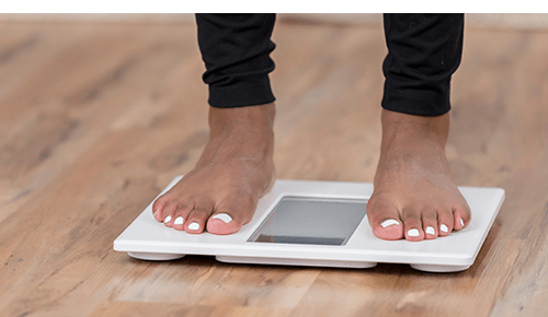 Person weighing themselves on a scale