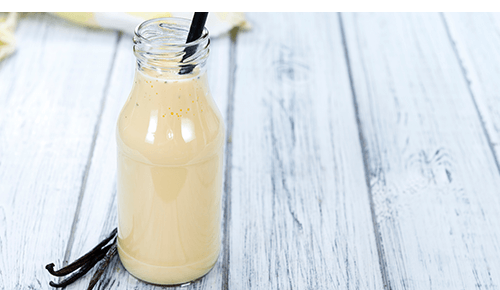 Glass bottle with vanilla protein shake and straw 