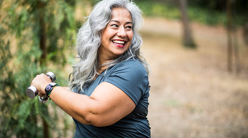 Smiling woman exercising with dumbbells outdoors Smiling woman exercising with dumbbells outdoors