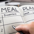 Closeup of person writing in a meal plan journal