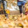 Closeup of two children kicking and playing in fall leaves on the ground