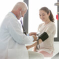 Teenager receiving a health checkup including blood pressure check from doctor