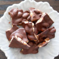 Pieces of dark chocolate nut clusters sitting on plate on table
