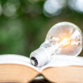 Closeup of open book with a shining lightbulb sitting on top