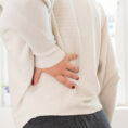 Closeup of person holding their lower back in pain