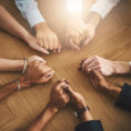 Closeup of group of people holding each others hands in support