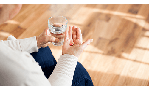 Person taking medication with a glass of water