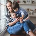 Parent with two children in their lap looking at a mobile phone