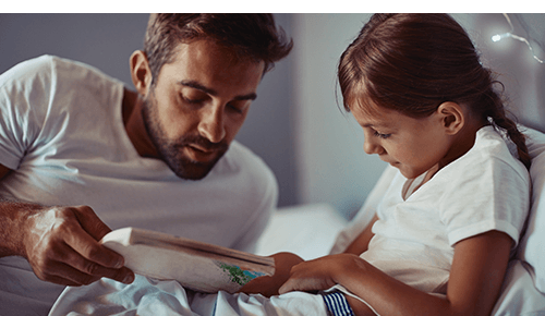 Father reading a book to a child at bedtime