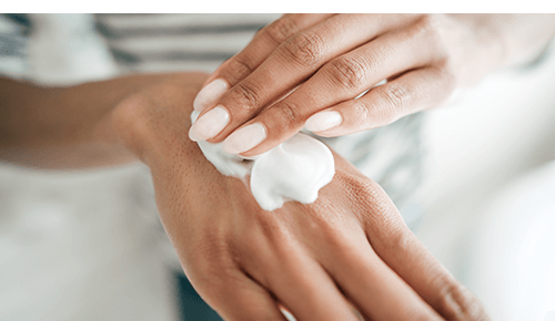 Person rubbing moisturizing lotion on back of hand