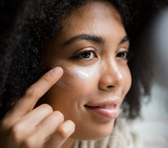 Woman putting skincare product on her cheek