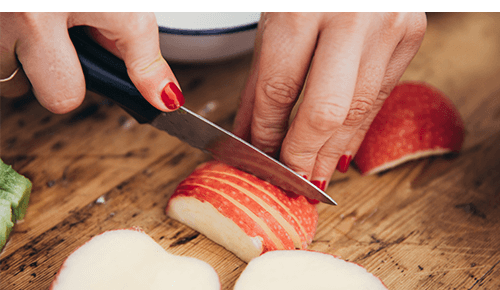 Closeup of a person slicing an apple with a knife