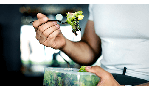 Closeup of someone using a fork to eat a salad