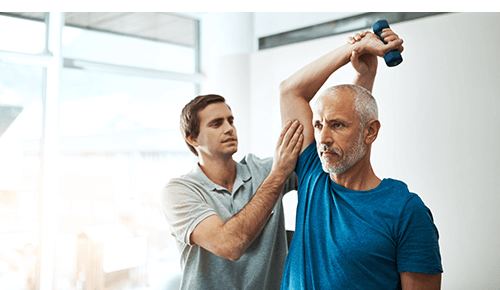 Man exercising with dumbbell with help from a physical therapist