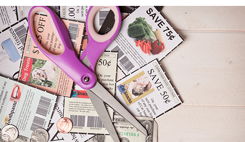 Closeup of scissors sitting on a pile of store coupons