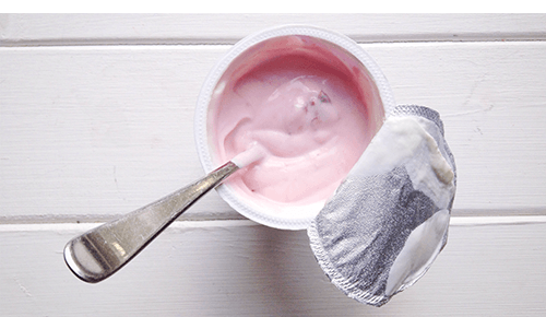 Container of flavored yogurt with spoon in it