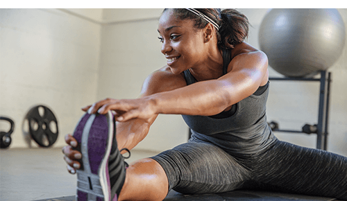 Woman stretching her legs after exercise in gym