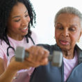 Woman raising a dumbbell with support from a physical therapist
